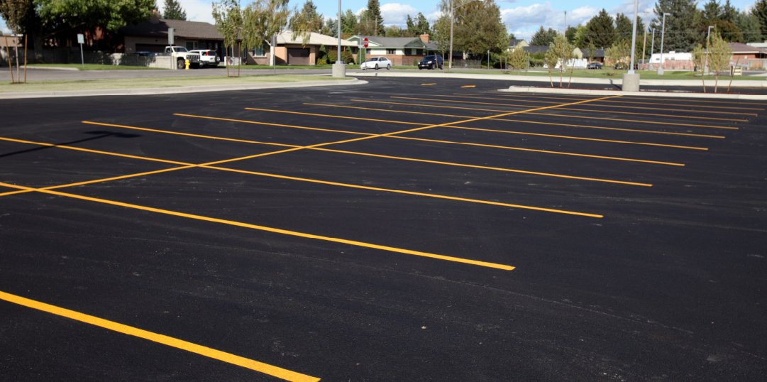Close-up of professional parking lot striping work showing precise yellow line application on dark asphalt in Baton Rouge, LA